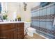 Cozy bathroom features a wood vanity, toilet, and patterned shower curtain for privacy at 8615 S 45Th Gln, Laveen, AZ 85339