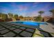Backyard featuring a sparkling pool, spa, tiled area, and modern landscaping under a vivid sky at 24437 N 94Th Ave, Peoria, AZ 85383