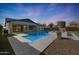 Twilight backyard showcasing a pool, spa, rock landscaping, and manicured trees at 24437 N 94Th Ave, Peoria, AZ 85383