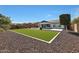 Spacious backyard with lush artificial turf, decorative rock landscaping, and manicured hedges at 24437 N 94Th Ave, Peoria, AZ 85383