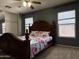 Bedroom with a wooden bed frame, ceiling fan, carpet flooring, and two bright windows at 1298 S 222Nd Ln, Buckeye, AZ 85326