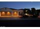 Charming home exterior illuminated at night, showcasing a two-car garage and manicured landscaping at 13117 W Micheltorena Dr, Sun City West, AZ 85375