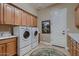 Well-organized laundry room features wooden cabinets and front-loading washer and dryer at 13117 W Micheltorena Dr, Sun City West, AZ 85375