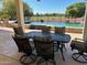 Covered patio with an outdoor dining table and chairs overlooking the beautiful pool and golf course views at 13117 W Micheltorena Dr, Sun City West, AZ 85375