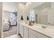 Light-filled bathroom with dual sinks, white cabinetry, a large mirror, and a shower/tub combo at 15579 W Williams St, Goodyear, AZ 85338