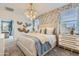 Stylish bedroom with contemporary chandelier lighting, neutral palette, a patterned accent wall, and dual windows at 15579 W Williams St, Goodyear, AZ 85338