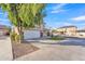 Exterior view of the house and manicured front yard featuring a shade tree, lush landscaping, and a spacious driveway at 16029 N 171St Dr, Surprise, AZ 85388