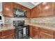 Kitchen featuring an electric range, wooden cabinets, and granite counters at 16029 N 171St Dr, Surprise, AZ 85388