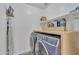 Modern laundry room with front loading washer/dryer, wooden countertop, and shelving at 16029 N 171St Dr, Surprise, AZ 85388