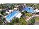 Aerial view of a community pool with a lap pool, lounge chairs, umbrellas, and modern clubhouse at 16681 W Charlotte Dr, Surprise, AZ 85387