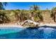 Backyard pool area with natural waterfall, rock features, and palm trees at 17704 W Tasha Dr, Surprise, AZ 85388