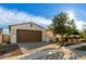 A well-manicured front exterior with a wide driveway, lush landscaping, and charming curb appeal at 19057 W Yucatan Dr, Surprise, AZ 85388