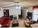 Cozy living room features a plush red sofa, a ceiling fan, and comfortable seating arrangement at 2121 N Center St # 138, Mesa, AZ 85201