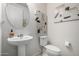 Modern powder room with a pedestal sink, round mirror, and decorative art at 26509 W Ponderosa Ln, Buckeye, AZ 85396