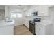 Modern kitchen with white cabinets, stainless steel appliances, marble countertops, and wood-look flooring at 2728 W Redfield Rd, Phoenix, AZ 85053