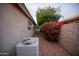 Well-kept side yard with an AC unit, gravel, and a vibrant bougainvillea bush adding color and charm at 4032 E Jojoba Rd, Phoenix, AZ 85044