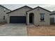 Single-story home featuring a dark garage door, arched entryway and desert landscaping at 4159 E Kolin Ln, San Tan Valley, AZ 85143