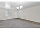 Spacious living room featuring neutral paint, modern lighting, and plush carpeting at 43524 W Bailey Dr, Maricopa, AZ 85138