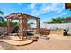 Backyard with pergola, outdoor dining table, built-in grill, spa, fire pit and paved patio at 4488 N 155Th Ave, Goodyear, AZ 85395