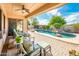 Covered patio with outdoor seating overlooking a kidney-shaped pool, lush greenery, and manicured landscaping at 4488 N 155Th Ave, Goodyear, AZ 85395