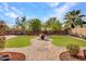 Well-manicured backyard featuring lush green grass, a brick patio, mature trees, and privacy fencing at 5137 W Quail Track Dr, Phoenix, AZ 85083