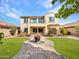 Two-story home with balcony boasts a lush backyard featuring a manicured lawn and brick pavers at 5137 W Quail Track Dr, Phoenix, AZ 85083