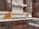 Close-up of modern kitchen featuring dark wood cabinets, gas cooktop and stainless steel hood at 5137 W Quail Track Dr, Phoenix, AZ 85083