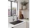 Modern kitchen sink with stainless steel faucet and a backyard view from a black frame window at 6114 N 8Th St, Phoenix, AZ 85014