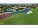 Aerial shot of a community clubhouse, pool with blue umbrellas, and adjacent lake on a lush golf course at 6614 W Victory N Way, Florence, AZ 85132