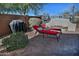 Private backyard featuring lounge chairs, grill, lush landscaping, and a charming stone fireplace at 6614 W Victory N Way, Florence, AZ 85132