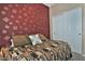 Comfortable bedroom featuring a patterned bedspread, a bold accent wall, and white closet doors at 6614 W Victory N Way, Florence, AZ 85132