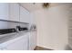 Well-organized laundry room featuring side by side washer and dryer, overhead cabinets, and storage shelves at 7950 E Camelback Rd # 310, Scottsdale, AZ 85251