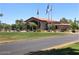 Exterior view of the community clubhouse with well-maintained landscaping and flag poles at 10122 E Michigan Ave # 19, Sun Lakes, AZ 85248