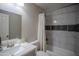 A bathroom with white marble-look tiling and a mosaic accent, features a shower with a bathtub and a vanity sink at 1624 W Minton St, Phoenix, AZ 85041