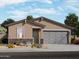 New construction home featuring a two-car garage, stone accents, desert landscaping and neutral color palette at 17426 W Eva St, Waddell, AZ 85355