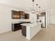 Modern kitchen with granite countertops, stainless steel appliances, and dark cabinetry with island lighting at 17426 W Eva St, Waddell, AZ 85355