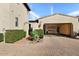 Charming home exterior featuring a two-car garage, beautiful landscaping, and a brick-paved driveway at 18650 N Thompson Peak Pkwy # 1028, Scottsdale, AZ 85255