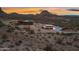 Expansive desert estate showcasing multiple buildings against a mountainous backdrop at sunset at 27194 N Bear Paw Pass, San Tan Valley, AZ 85144