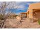 Scenic backyard featuring desert landscaping, covered patio with stone accents, and a paved walkway leading to the house at 3086 N Herrala Way, Apache Junction, AZ 85119