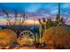 Desert garden featuring native plants, cacti, rocks, and a charming wooden wagon wheel decoration at 3086 N Herrala Way, Apache Junction, AZ 85119