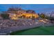 Inviting home exterior with meticulously landscaped rock yard, mature desert trees, and a putting green at 3086 N Herrala Way, Apache Junction, AZ 85119