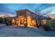Stunning exterior shot of a home with unique architectural features, beautiful desert landscaping, and warm lighting at dusk at 3086 N Herrala Way, Apache Junction, AZ 85119