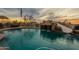 Inviting pool area features rock waterfall, desert views and sunset skies at 3086 N Herrala Way, Apache Junction, AZ 85119