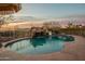 Inviting pool area features rock waterfall, desert views and sunset skies at 3086 N Herrala Way, Apache Junction, AZ 85119