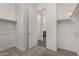 Walk-in closet with carpet and view into bathroom area with gray tile and dark cabinetry at 31476 N Hayweather Ln, San Tan Valley, AZ 85143
