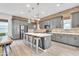 Modern kitchen features grey cabinets, exposed brick backsplash, stainless steel appliances and a large island with seating at 367 N 157Th Ln, Goodyear, AZ 85338