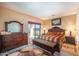 A spacious main bedroom with a dark wood dresser, bench, and a sliding glass door to the patio at 40558 W Parkhill Dr, Maricopa, AZ 85138