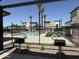 Community pool and BBQ area with modern buildings, palm trees, and black wrought iron fence at 651 N Ironwood Dr # 1, Apache Junction, AZ 85120