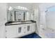 Bathroom featuring double sinks, vanity lighting, large mirrors, and a separate shower at 8611 W Village Dr, Peoria, AZ 85382