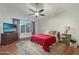 Comfortable bedroom with neutral walls, ceiling fan, a large window and a red comforter at 8611 W Village Dr, Peoria, AZ 85382